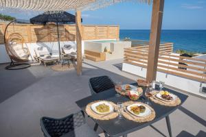 a table with plates of food on a patio with the ocean at Mnḗmē Suites & Villas in Kastrí