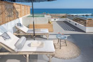 a patio with chairs and a table and the ocean at Mnḗmē Suites & Villas in Kastrí
