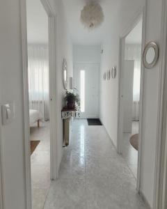 un pasillo con paredes blancas y una habitación con espejo en Casa Tonino: Encantadora casa junto al Río Duero en Zamora