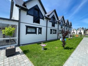 a row of houses in a yard with grass at Amelia Domki in Sianozety