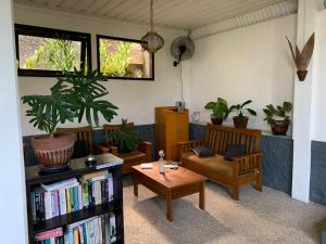 a living room with a table and chairs and a book shelf at Kebun Rohani Cottages in Senggigi