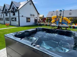 una bañera de hidromasaje en un patio con parque infantil en Amelia Domki en Sianozety