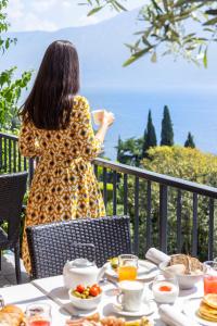 una donna seduta a un tavolo con cibo per la colazione di Hotel Meandro - Lake View a Gargnano