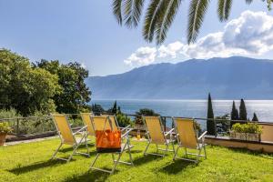 un gruppo di sedie seduti sull'erba vicino all'acqua di Hotel Meandro - Lake View a Gargnano