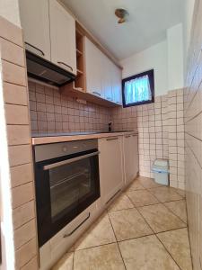 a kitchen with a stove and a tv on the wall at Apartman Dolac in Karlobag