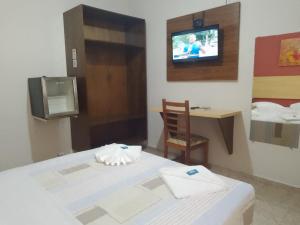 Hotel Venice Ubatuba في أوباتوبا: غرفة بها سرير وتلفزيون على الحائط