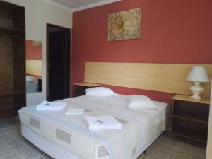 um quarto com uma cama branca e uma parede vermelha em Hotel Venice Ubatuba em Ubatuba