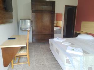 een kamer met een bed en een bureau en een bed bij Hotel Venice Ubatuba in Ubatuba