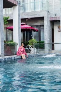 una mujer sentada en el borde de una piscina en Ninh Bình Premier hotel en Ninh Binh