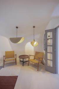 Oia Waves by SV في أويا: غرفة بها كرسيين وطاولة وأضواء