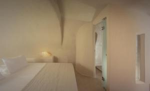 a white bedroom with a bed and a door at Oia Waves by SV in Oia