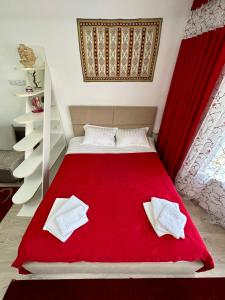 a bedroom with a red bed with a red blanket at Raduga West 'Amber' Apartment in Koshkolʼ
