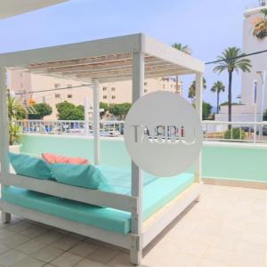 a canopy bed with pillows on a balcony with a pool at Tabbu ibiza apartments in Playa d'en Bossa