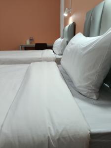 um quarto com 2 camas com lençóis brancos e almofadas em โรงแรม เดอะพีช / The Peach hotel em Phetchaburi