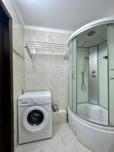 a bathroom with a washing machine and a shower at Raduga West 'Amber' Apartment in Koshkolʼ