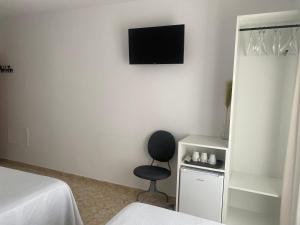 Habitación con silla y TV en la pared. en Hostal Andalucia, en Nerja