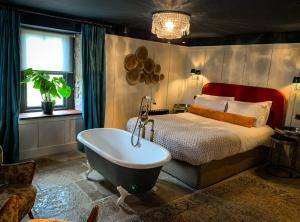 The Joiners Arms في Chathill: غرفة نوم مع سرير وحوض استحمام بجانب سرير