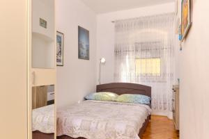 a small bedroom with a bed and a window at SNJEŽANA in Mali Lošinj
