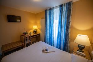 a bedroom with a bed and a lamp and a window at Logis Hotel Le Continental in Châteauroux