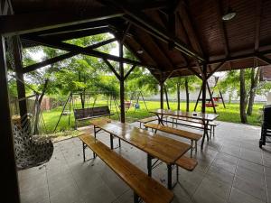 a group of picnic tables in a pavilion with a playground at Alföldi Vendégház - Dévaványa in Dévaványa