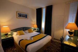 Habitación de hotel con 1 cama y 2 lámparas en Logis Hotel Le Continental en Châteauroux