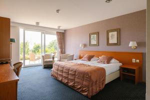 a hotel room with a bed and a large window at Landhotel Heuvelzicht in Schin op Geul