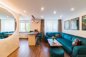 a living room with a blue couch and a kitchen at E. D. Elite Apartment in Šiauliai
