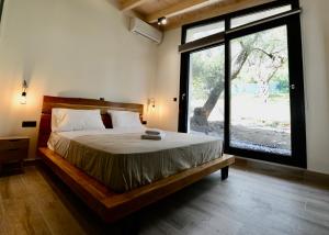 a bedroom with a bed and a large window at Stablus house in Alykes Potamou