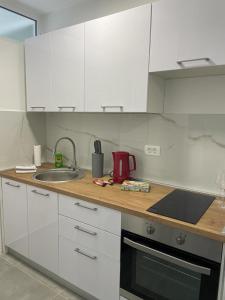 eine Küche mit weißen Schränken und einem Waschbecken in der Unterkunft Apartman Stela in Knin