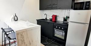 een keuken met een witte koelkast en een zwarte kachel bij Golden - Éden - superbe 2 pièces de standing en hypercentre in Vichy