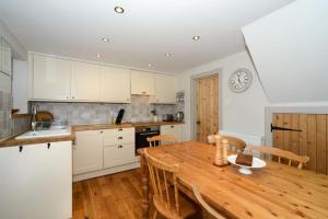 a kitchen with a wooden table and a clock on the wall at Mrs Moll's Cottage in Earlston +11 photos