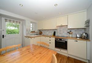 a kitchen with a wooden table and white cabinets at Mrs Moll's Cottage in Earlston