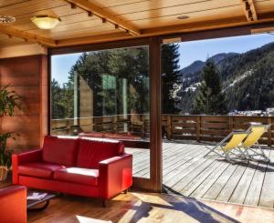a living room with a red couch on a deck at Hotel Club Regina E Fassa in Mazzin