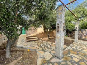 einen Steinweg mit einem Baum und einer Steinsäule in der Unterkunft Rose Guesthouse in Al ‘Aqar