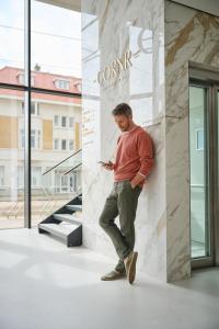 Ein Mann, der sich an die Wand lehnt und sein Handy ansieht. in der Unterkunft The CORNR Hotel in Nieuwpoort