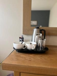 a tray with two cups and a tea kettle on a counter at Charnock Farm Motel in Leyland