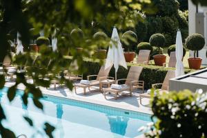 einen Pool mit Stühlen und Sonnenschirmen neben einem Pool in der Unterkunft Hotel Angleterre & Résidence in Lausanne