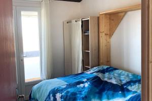 een slaapkamer met een bed met een blauw dekbed en een raam bij Maison Saintes Maries de la Mer in Saintes-Maries-de-la-Mer