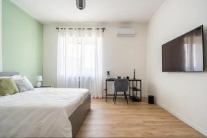 a white bedroom with a bed and a television at Beno House Brescia in Brescia