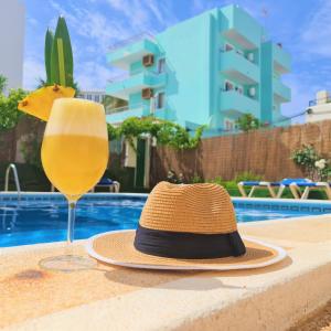 a hat and a glass of wine next to a pool at Tabbu ibiza apartments in Playa d'en Bossa