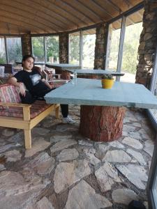 Ein Mann, der auf einer Bank neben einem großen Tisch sitzt. in der Unterkunft Hergül Holiday Village in Gazipasa