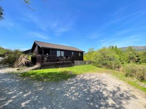 a black house with a porch and a driveway at Pass the Keys Beautiful Golf and Beach Lodge in Stunning Location in Dalbeattie