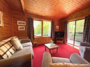 a living room with a couch and a tv at Pass the Keys Beautiful Golf and Beach Lodge in Stunning Location in Dalbeattie