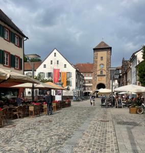 uma rua da cidade com mesas e cadeiras e uma torre do relógio em Petras Ferienwohnung em Villingen-Schwenningen