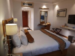 ein Schlafzimmer mit einem großen weißen Bett und einem TV in der Unterkunft Hotel Razmoni Isha Kha International in Dhaka