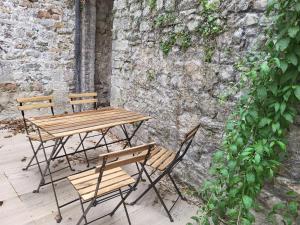 een houten tafel en stoelen naast een stenen muur bij Duplex neuf 2 chambres HUY in Huy