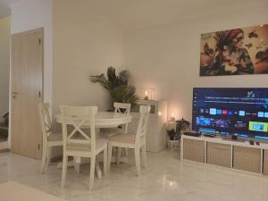 ein Esszimmer mit einem weißen Tisch und einem TV in der Unterkunft Duplex neuf 2 chambres HUY in Huy