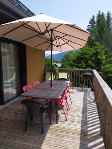 une table en bois avec des chaises et un parasol sur une terrasse dans l'établissement Ô ! Chalet des Rêves..., à La Féclaz