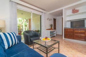 a living room with a blue couch and a glass table at Barca Trencada -A3- in Cala Mondrago