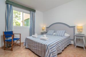 een slaapkamer met een bed, een stoel en een raam bij Barca Trencada -A3- in Cala Mondrago